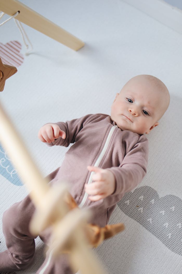 Charming infant in a sleepsuit lying on a soft play mat in a cozy nursery environment.